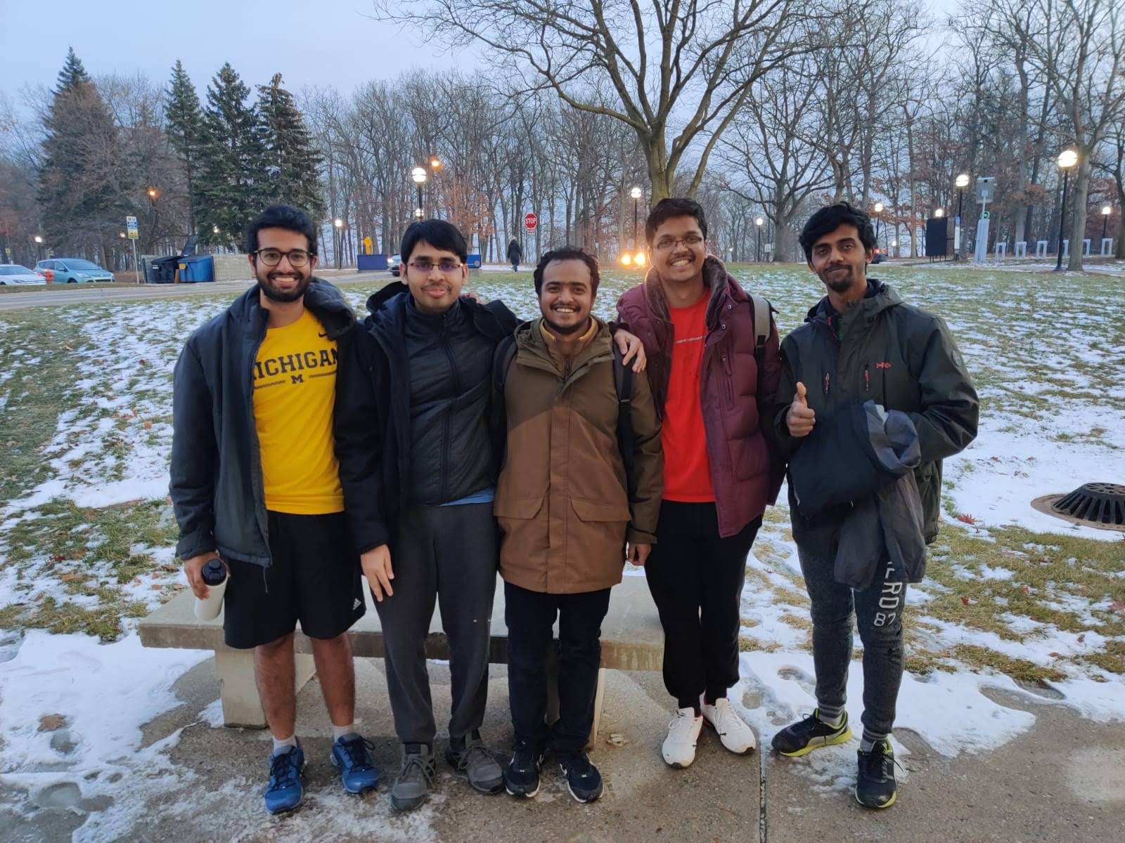 5 men standing on campus during snowfall in Michigan gear