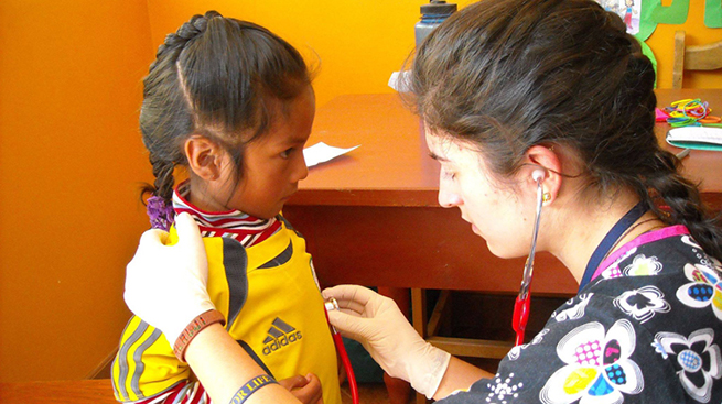 Leila Syal examining child with stethoscope