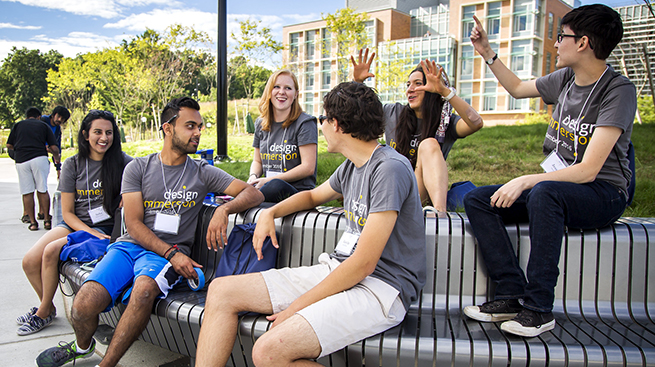 Students sitting on bench on campus laughing