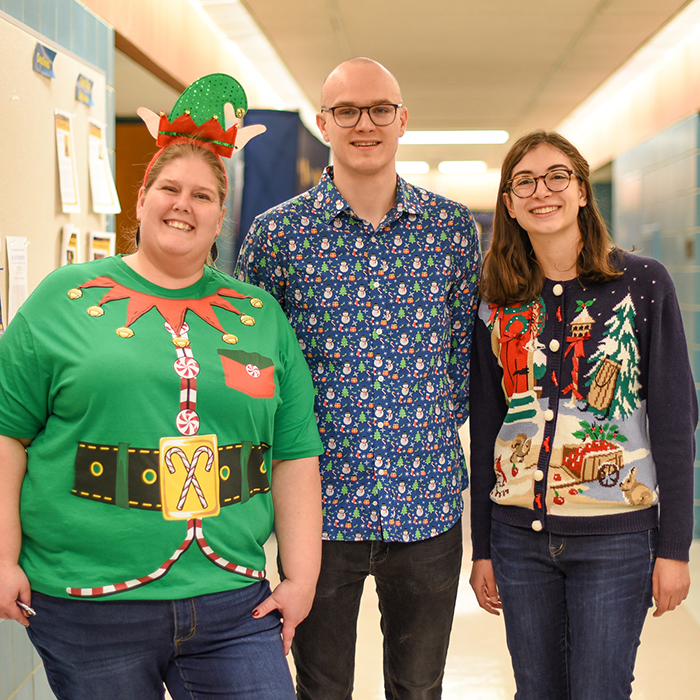 three people in holiday sweaters