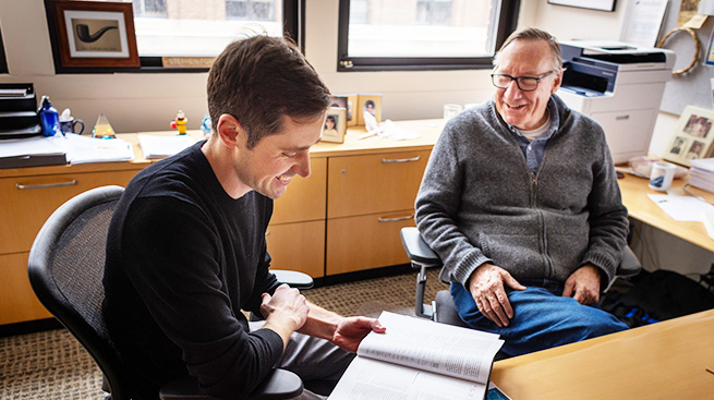 Two researchers at a desk discussing their company.